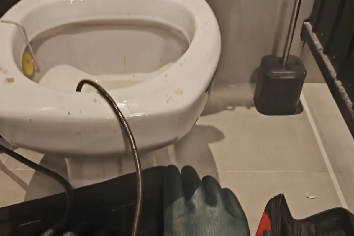 Equipamento profissional de desentupimento posicionado ao lado do vaso sanitário no banheiro